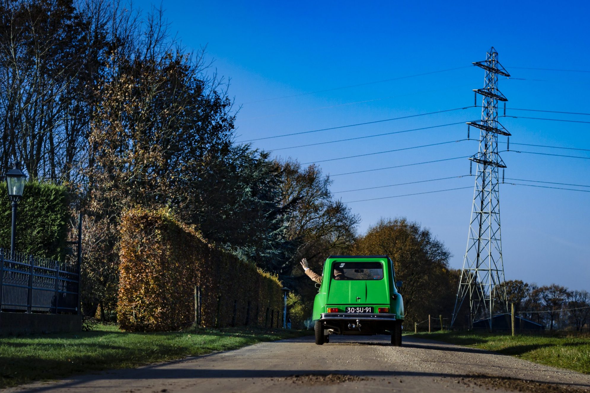 Een groene klassieke auto op een landweg
